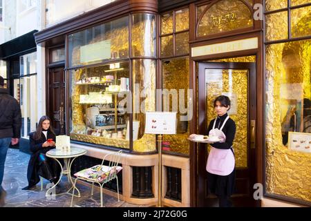Die Kellnerin serviert ein Tablett mit Speisen und Getränken für Gäste, die am Tisch vor dem Burlington Arcade Shop Restaurant Piccadilly London England Großbritannien Großbritannien sitzen Stockfoto