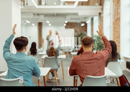 Studenten heben ihre Hände für Antwort Stockfoto