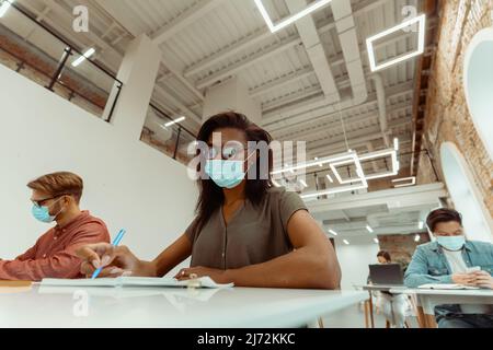 Hübsche junge Schülerin in Brille, die im Klassenzimmer sitzt Stockfoto