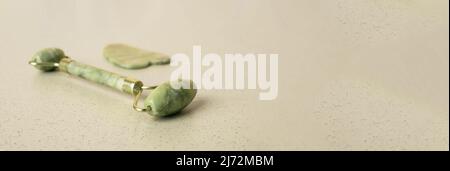 Gua Sha Massage Steininstrumente. Abstreifer und Rolle auf Banner, Hintergrund mit Kopierplatz. Stockfoto