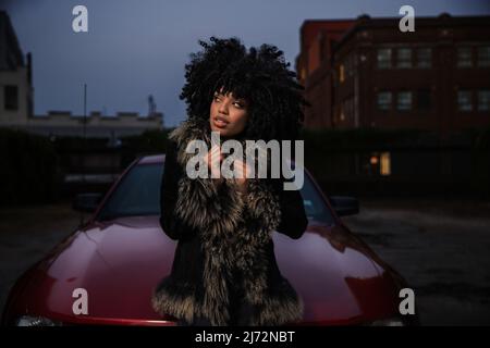 Porträt einer jungen afroamerikanischen Frau mit ihrem Auto. Stockfoto