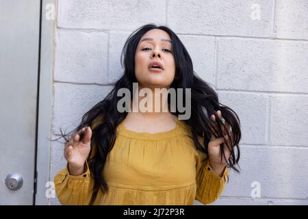 Porträt einer jungen Frau, die ihre Hände durch ihre langen Haare läuft. Stockfoto