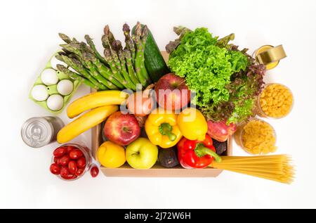 Spendenbox mit frischem Obst und Gemüse, Eiern, Pasta und Konserven. Lebensmittelzustellung und Einkaufskonzept. Vegetarische Lebensmittel, isoliert Stockfoto