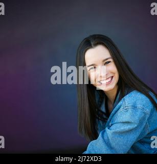 Eine schöne glückliche Teenager Brünette Mädchen aus der Nähe stehen gegen eine lila blaugrün Wand mit Kopierer Platz Stockfoto