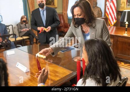 Washington, Vereinigte Staaten von Amerika. 04. Mai 2022. Die US-Vizepräsidentin Kamala Harris, Center, blickt auf die Goldmedaille der Bobmedaille von Olympia, bevor sie die Athleten, die an den Olympischen Sommerspielen und Paralympics 2020 in Tokio, den Olympischen Winterspielen und den Paralympics 2022 in Peking, im Weißen Haus am 4. Mai 2022 in Washington, D.C. begrüßt. Quelle: Lawrence Jackson/White House Foto/Alamy Live News Stockfoto