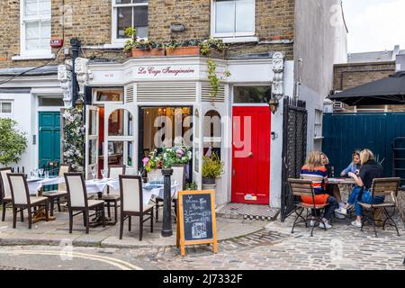 Gäste, die draußen speisen, genießen köstliche Speisen im La Cage Imaginaire Restaurant, einem französischen Bistro in der malerischen gepflasterten Straße des Flask Walk Hampstead NW3 Stockfoto