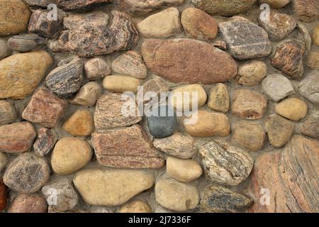 Nahaufnahme Einer Steinmauer, die aus bunten Felsen und Zementmörtel gebaut wurde. Hintergrundtextur Stockfoto