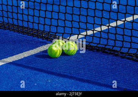Blauer Paddle-Tennisplatz, drei Bälle in der Nähe des Netzes Stockfoto