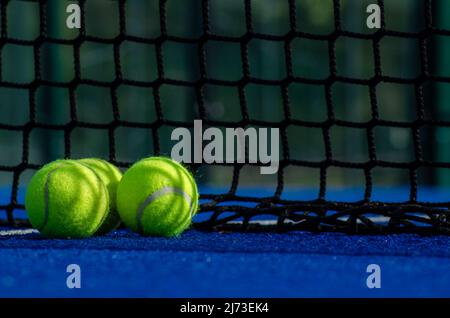 Blauer Paddle-Tennisplatz, drei Bälle in der Nähe des Netzes Stockfoto