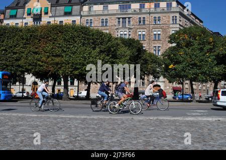 Vier Personen radeln im Sommer auf Radwegen am Strandvägen, am Ufer von Ostermalm, Stockholm, Schweden. Stockfoto