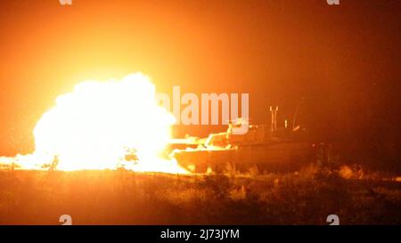 Ein M1A2 SEPv2 Abrams Tank feuert während des Nachtfeuers von Tabelle VI des Sullivan Cup in Fort Benning, Georgia, 4. Mai 2022. Der Sullivan Cup erfordert die Beherrschung einzelner Aufgaben, die technische und taktische Kompetenz sowie die Fähigkeit, eine Reihe von Manövern, Erhaltungsfähigkeiten und Geschützenkenntnissen unter Beweis zu stellen. (USA Foto der Armee von Staff Sgt. Justin McClarran) Stockfoto