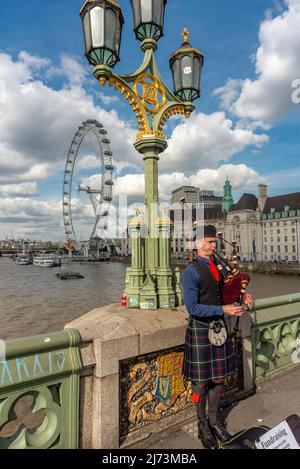 London, England, UK-August 21 2019: Ein junger Schotte in traditioneller Kleidung spielt Dudelsäcke für Passanten auf einer der berühmtesten Brücken Londons, um Rais zu spielen Stockfoto