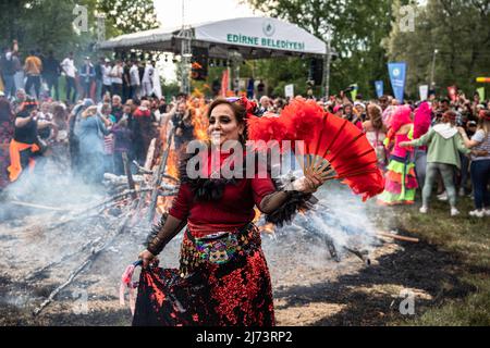 Eine tanzende Frau sah einen roten Ventilator vor dem Feuer halten. Das Kavava- und das H?drellez-Festival, das zu den Veranstaltungen gehört, die den Frühling begrüßen, findet jedes Jahr am 5.. Und 6.. Mai statt. Stockfoto