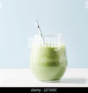 Gesunder grüner Smoothie im Glas mit Stroh auf blauem Hintergrund. Vegetarische gesunde Lebensweise Konzept. Erfrischende Getränk Quadrat. Schnelle Snack Stockfoto