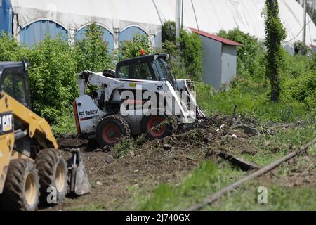 Bukarest, Rumänien - 1. Mai 2022: Arbeiter säubern ein Gebiet von Vegetation und Eisenbahnschutt für zukünftige Bauarbeiten. Stockfoto