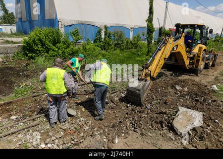 Bukarest, Rumänien - 1. Mai 2022: Arbeiter säubern ein Gebiet von Vegetation und Eisenbahnschutt für zukünftige Bauarbeiten. Stockfoto