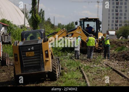 Bukarest, Rumänien - 1. Mai 2022: Arbeiter säubern ein Gebiet von Vegetation und Eisenbahnschutt für zukünftige Bauarbeiten. Stockfoto