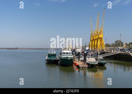 HUELVA, SPANIEN - 18. APRIL 2022: Ruhiger Rio Tinto-Fluss mit Hafenkranen und Guardia Civil Polizeibooten im Hafen von Huelva Stockfoto