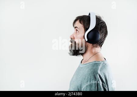 Seitenansicht des bärtigen Mannes, der Musik in Kopfhörern hört. Stockfoto