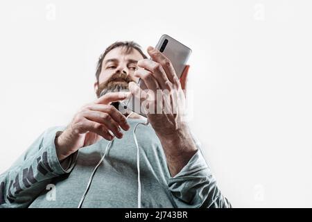 Bärtiger Mann mit einem Smartphone in den Händen. Seriöser Mann nutzt Smartphone. Selektiver Fokus. Stockfoto