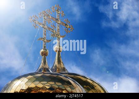 Orientalisch-orthodoxe Kreuze auf goldenen Kuppeln des Tempels gegen den blauen Himmel mit Wolken. Trinity Cathedral of Raifa Monastery, Tatarstan, Russland. Stockfoto