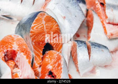 Forelle, in Stücke geschnitten, auf Eis auf dem Ladentisch gelegt. Rote Fischstücke in Nahaufnahme. Stockfoto