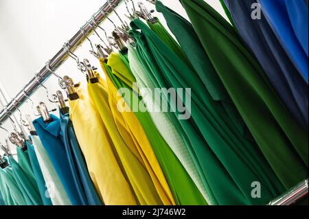 An der Theke hängen Muster von grün-gelben und blauen Stoffen Stockfoto