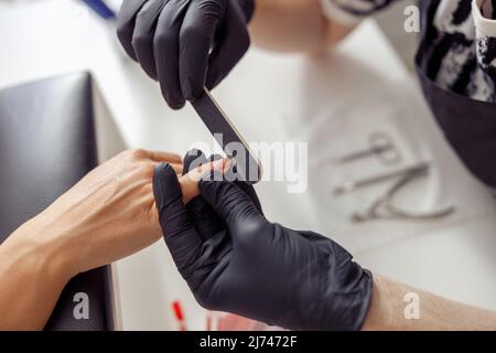 Erfahrener Maniküre-Meister, der im Studio an Nägeln arbeitet Stockfoto