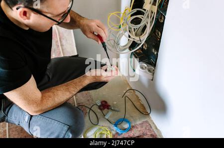 Techniker mit Schraubendreher und Klemmenleiste zur Installation des Telekommunikationskastens Stockfoto