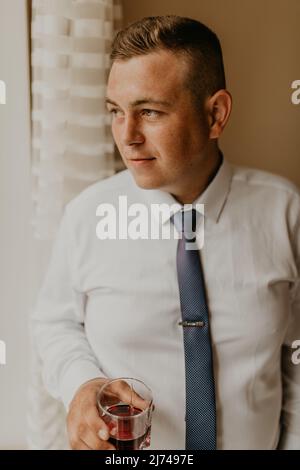 Blonde europäischen kaukasischen jungen Bräutigam im Hemd Business-Anzug mit Krawatte Vorbereitung für die Hochzeit. Vorbereitung für wichtige Veranstaltung Treffen drinnen Sorgen. A Stockfoto