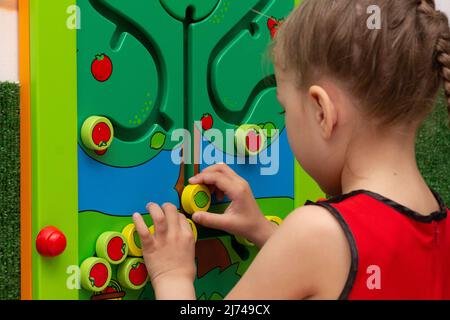 Kind spielt mit Holzlabirinta im Spielzentrum im Inneren Stockfoto