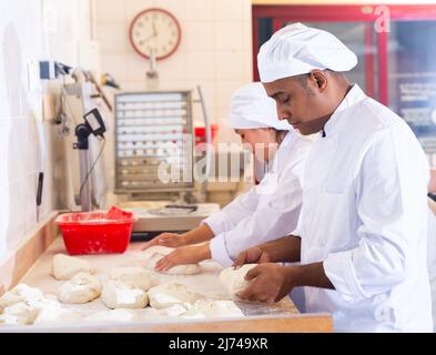 Hispanischer Bäcker knetet und bildet Teig zum Backen von Brot Stockfoto