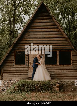 Europäischer kaukasischer junger Mann Bräutigam in blauem Anzug und schwarzhaarige Frau Braut in weißem Hochzeitskleid mit langem Schleier und Tiara auf dem Kopf. Frisch Vermählt Stockfoto