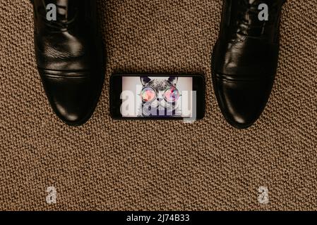Schwarze Stiefel sitzen auf einem braunen strukturierten Boden. Fly kriecht in der Nähe von Schuhen. Männer klassische Mode formale Schuhe. Klassischer Stil Eheringe liegen im Bild Stockfoto
