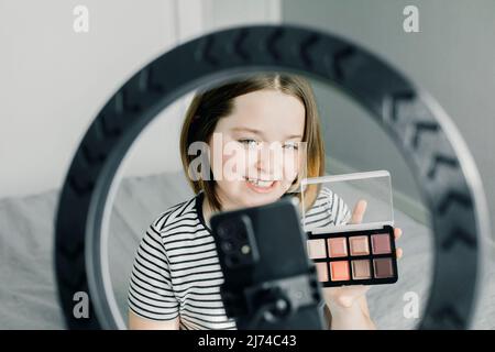 Teen girl Aufnahme Video review Blog mit Smartphone und LED-Lampe zu Hause. Blogging, Videoblog, Make-up-Konzept. Stockfoto