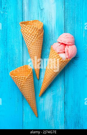 Beere und Sahneeis und Waffelbecher auf blauem Hintergrund. Stockfoto