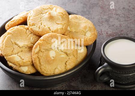 Weiche Plätzchen mit Macadamianüssen und weißer Schokolade, serviert mit Milch aus nächster Nähe auf dem Tisch. Horizontal Stockfoto