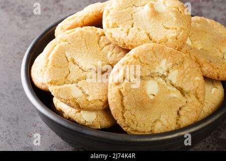 Weiße Schokoladenkekse und Macadamianüsse auf dem Teller auf dem Tisch in Nahaufnahme. Horizontal Stockfoto