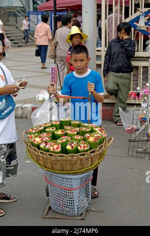 Thai Boy verkauft Rosen in Bananenblätter gewickelt auf dem Chatuchak Markt, Thailand, Bangkok Stockfoto