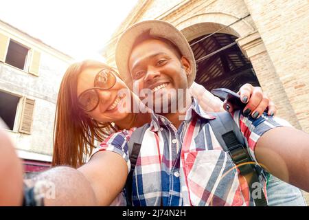 Multirassisches Paar, das Selfie bei einem Ausflug in die Altstadt macht - Fun-Konzept mit alternativen Modereisenden - indischer Freund mit kaukasischer Freundin - warm Stockfoto
