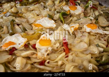 Viele Kartoffeln mit Zwiebeln und Eiern in einer großen Pfanne. Kartoffel für die Armen. Typisches Gericht der spanischen Messen. Stockfoto