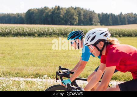 Professionelle kaukasische Rennradfahrer Paar Reiten auf einer asphaltierten Straße auf dem Land, Tracking-Schuss. Stockfoto