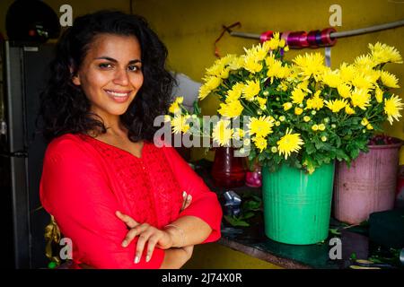 Fröhliche junge Frau Brünette Floristin Verkauf von Blumen in einem Blumenladen Stockfoto