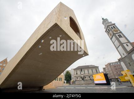 06. Mai 2022, Bayern, Augsburg: Neben dem Perlachturm und dem Augustusbrunnen steht ein freischwebendes Holzhaus. Im Pavillon auf dem Rathausplatz werden mehrere Wochen lang zahlreiche Veranstaltungen anlässlich des Jahrestages der ältesten sozialen Siedlung der Welt stattfinden. Foto: Stefan Puchner/dpa Stockfoto