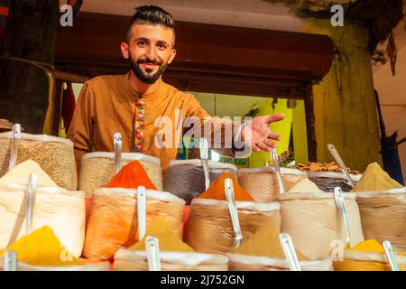 indischer Sallerman zeigt seinen kleinen Laden auf dem arambol goa Markt Stockfoto