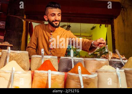 indischer Sallerman zeigt seinen kleinen Laden auf dem arambol goa Markt Stockfoto