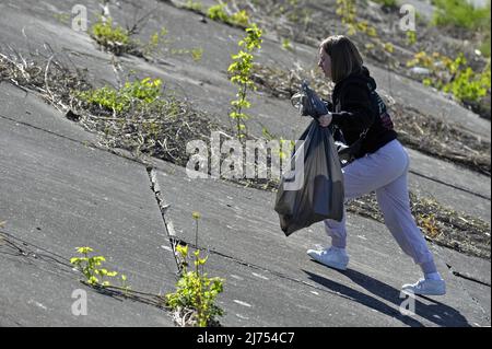 VINNYZJA, UKRAINE - 5. MAI 2022 - Ein Freiwilliger holt Müll entlang der Uferpromenade des Flusses Pivdennyj Buh, Vinnyzja, Zentralukraine, ab. Dieser Phot Stockfoto