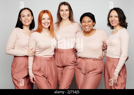 Porträt von lächelnden schönen echten Frauen umarmen einander vor isoliertem Hintergrund, internationale Frauen Tag Konzept Stockfoto