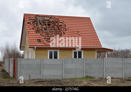 Dorf Dmytriwka, Region Kiew, Ukraine - 03. April 2022: Das Dach des Hauses wurde durch die russischen Besatzer durch Beschuss beschädigt. Stockfoto