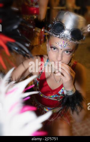 Karneval in Sitges in Spanien: Nahaufnahme einer jungen Frau in schickem Kleid, die mit einem seltsamen Ausdruck auf die Kamera starrt. Stockfoto